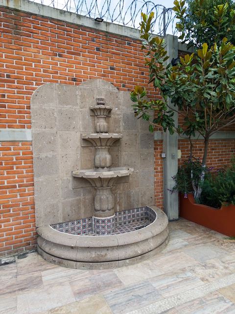 Fuente de cantera empotrada al muro, con azulejo de talavera