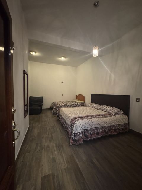Habitación con dos camas y sillón, dentro del terreno