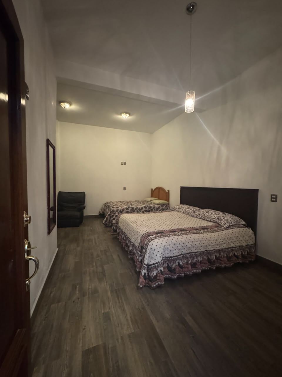Habitación con dos camas y sillón, dentro del terreno