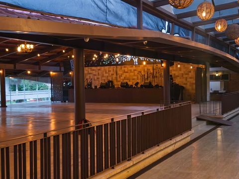 Pista de baile de madera elevada, con barandal, frente al escenario
