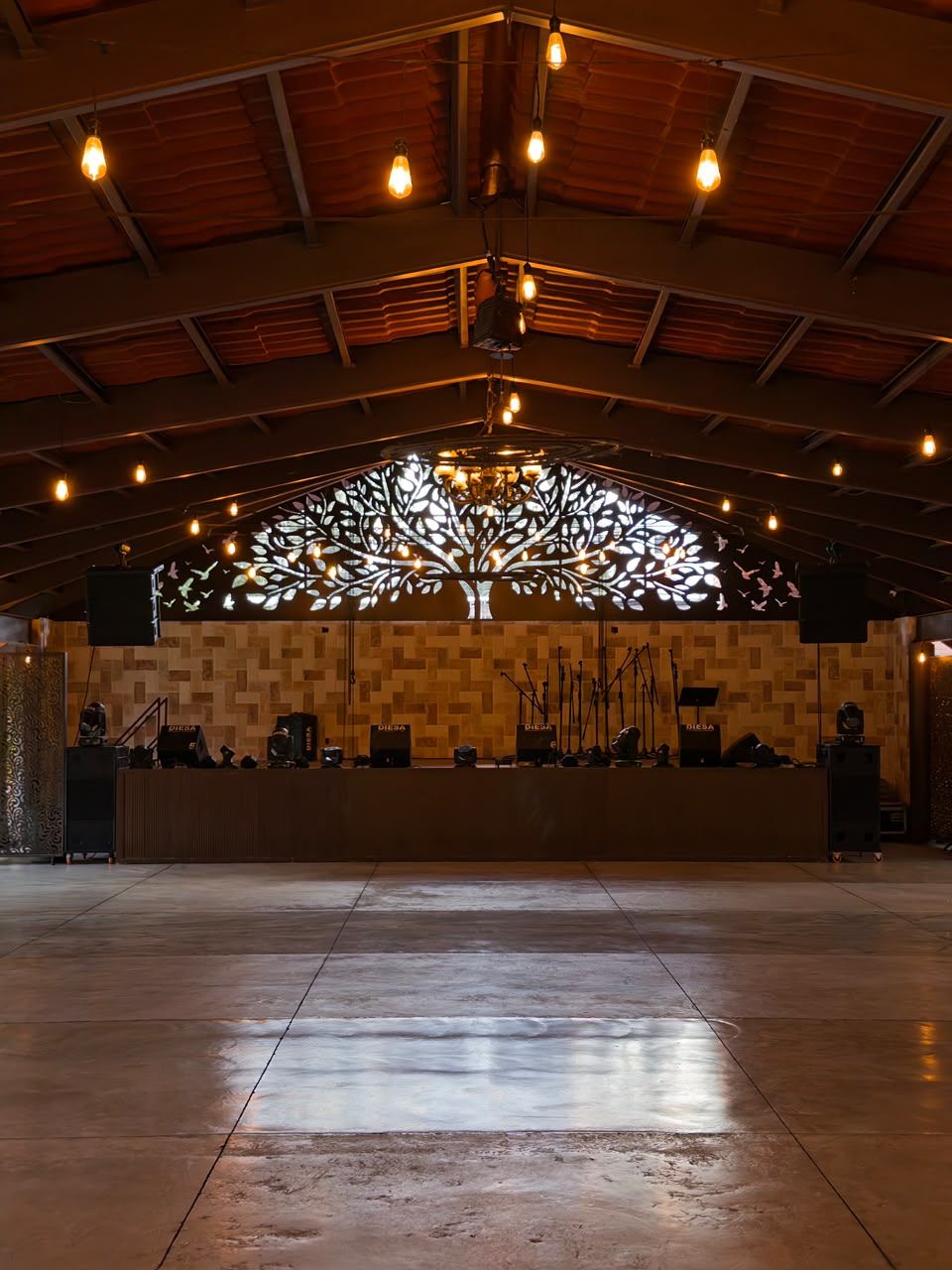 El salón vacío de noche, con el escenario y el árbol calado iluminados