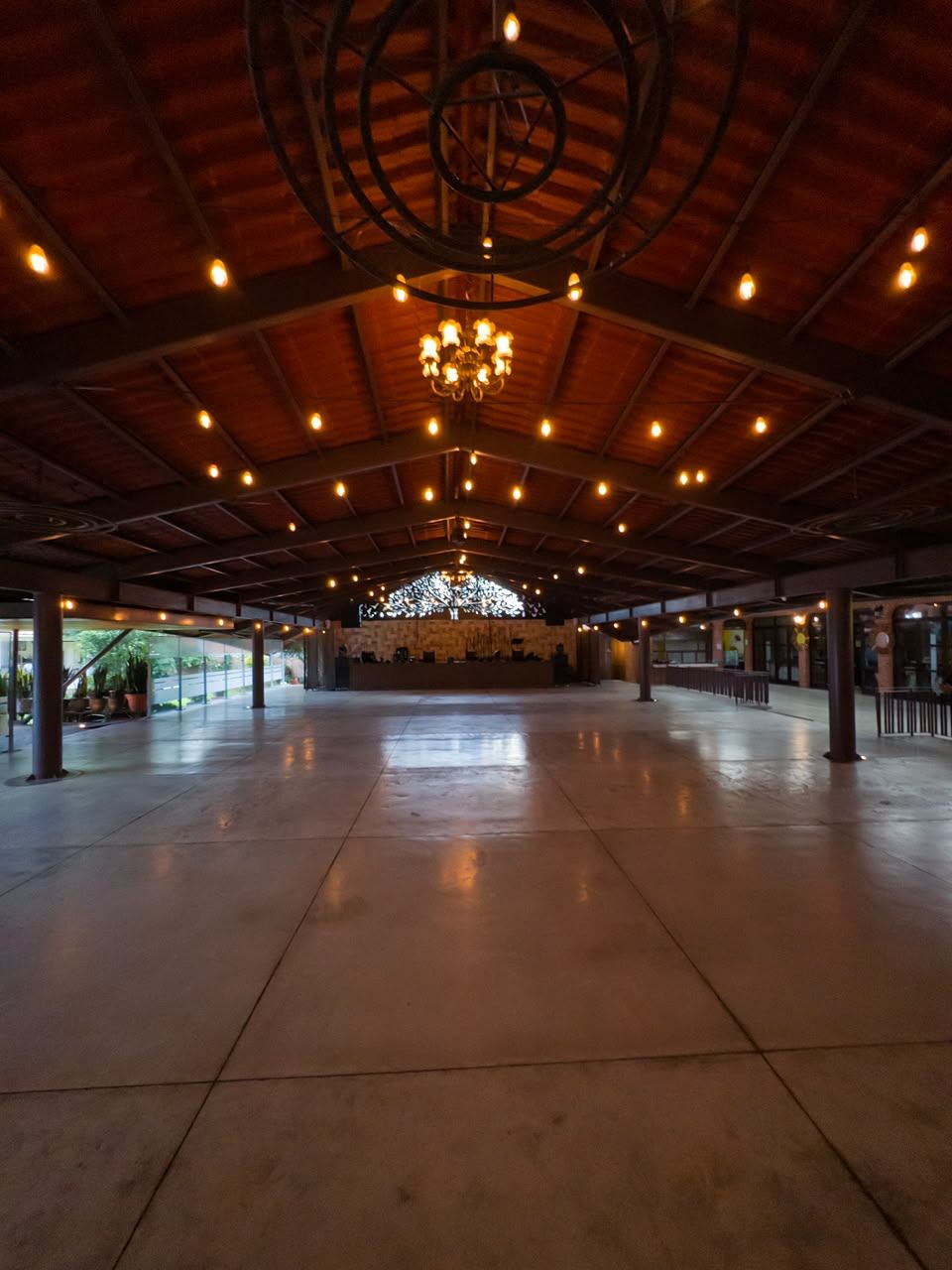 Interior del salón techado a dos aguas, con vigas de madera y series de foco cálido